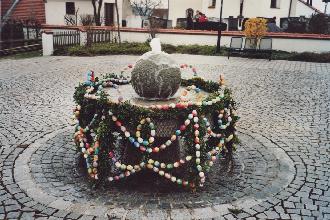geschmückter Mühlstein-Dorfbrunnen